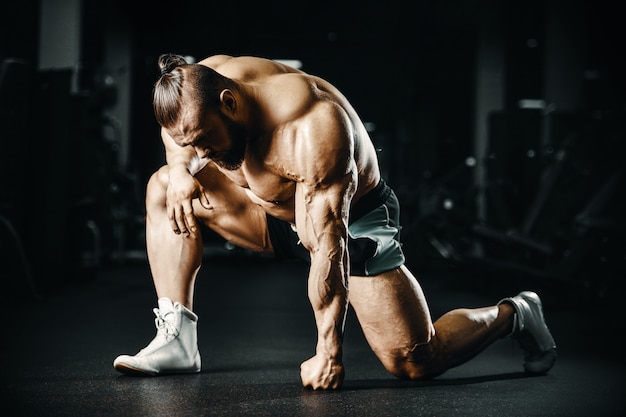 Photo bodybuilder strong man pumping up biceps muscles