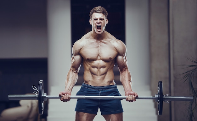 Bodybuilder strong man pumping up biceps muscles