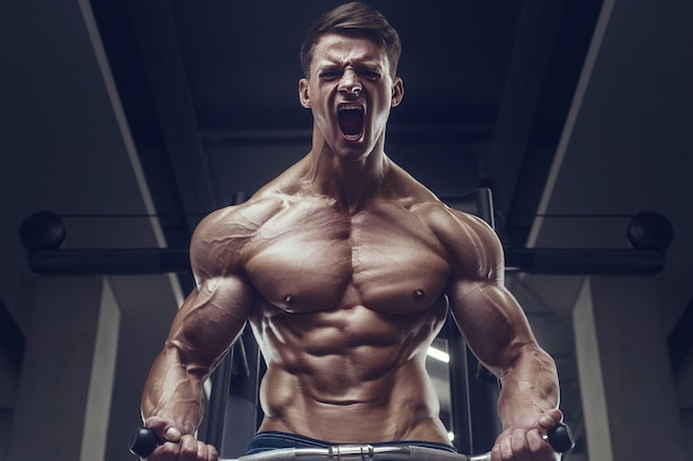 Bodybuilder strong man pumping up biceps muscles