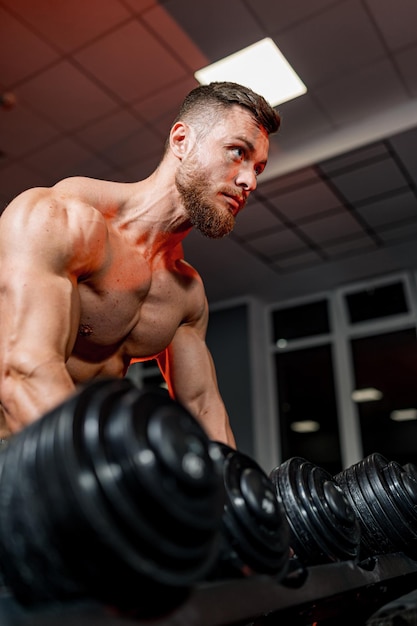 Bodybuilding person working out with big weights Strong muscular man training in the gym