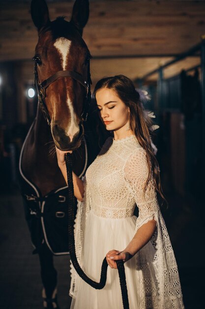 A boho bride poses with a horse in a stable