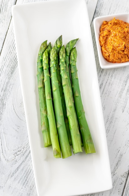 Boiled asparagus on the white serving dish with romesco sauce