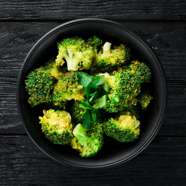 Boiled broccoli in a black plate On a black background Top view Free space for your text