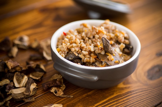 boiled buckwheat with organic forest dried mushrooms in a ceramic bowl on a wooden table