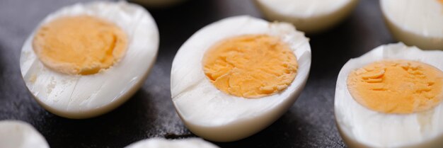 Boiled chicken eggs cut in half on dark background