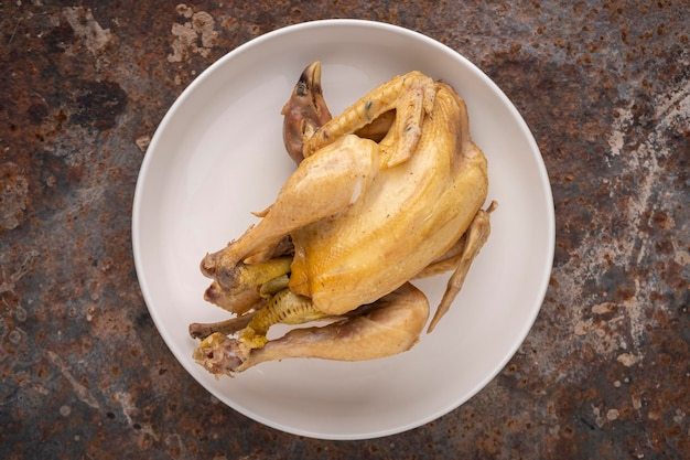 Boiled chicken in simply ceramic plate on rusty texture background top view flat lay