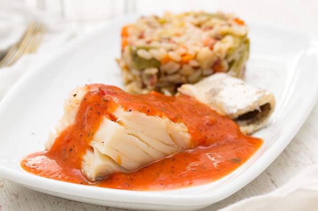 Boiled cod fish with tomato sauce and rice on plate