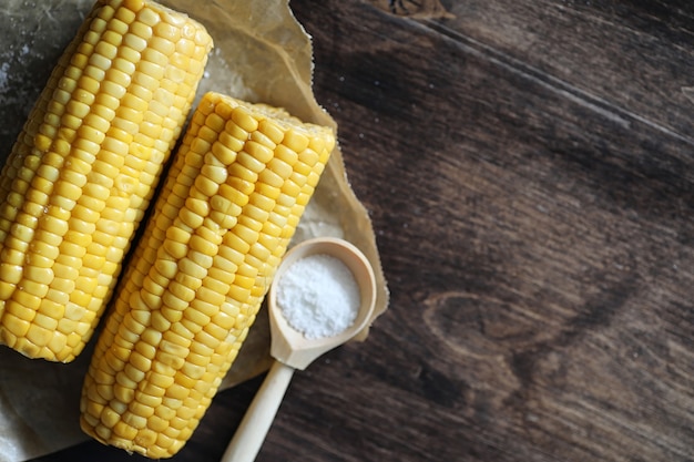 Boiled corn cob with salt on a wooden table