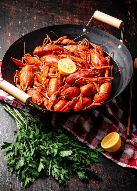 Boiled crayfish in a pot with parsley and lemon