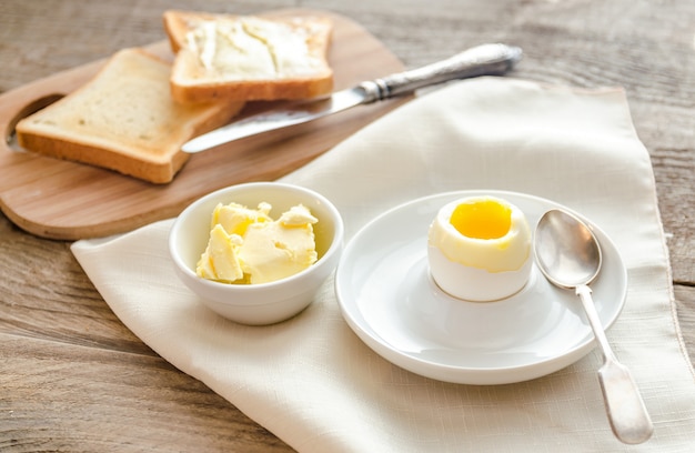 Boiled egg with crispy toasts on the wooden table