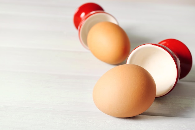 Boiled eggs in holders on light background