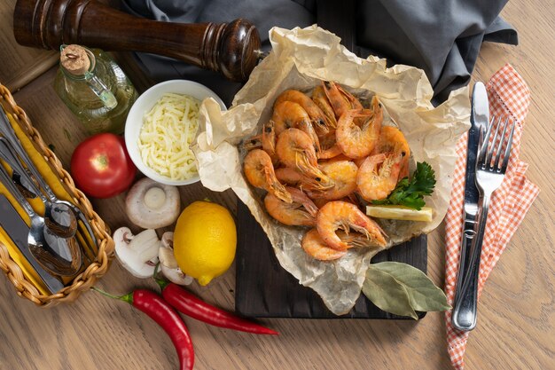 Photo boiled king prawns with lemon in baking paper on a wooden chopping board