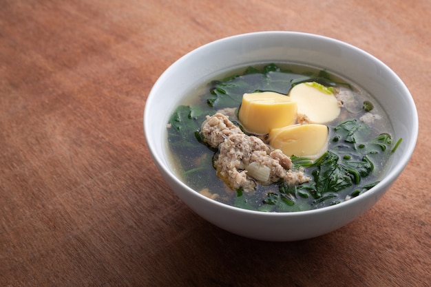 Boiled minced pork and tofu soup with gourd in white bowl on wooden table, Thai food, Healthy food.