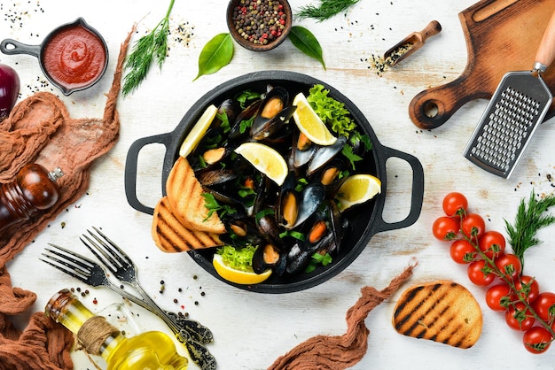 Boiled mussels with garlic parsley and lemon in a frying pan Top view Free space for your text