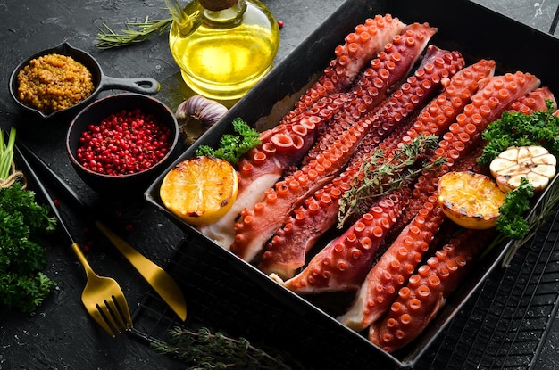 Boiled octopus tentacles with spices and herbs in a metal baking dish Top view Flat lay