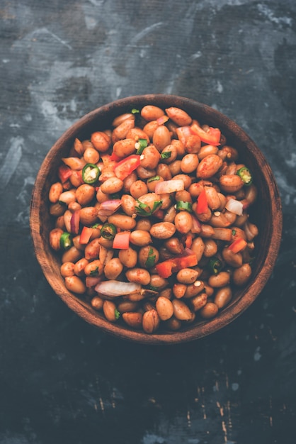 Boiled Peanut Chaat or Chatpata sing dana or shengdana or mungfali. served in a ceramic bowl over moody background