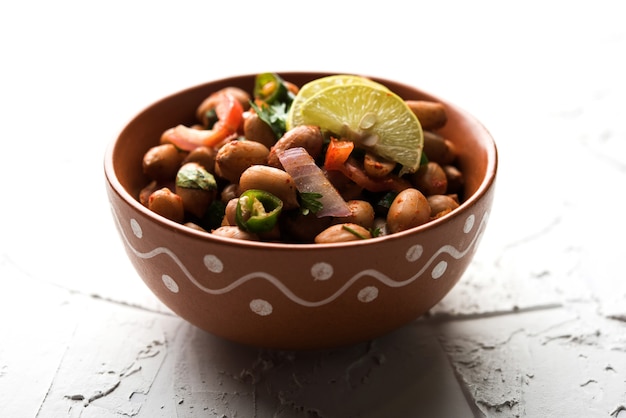 Boiled Peanut Chaat or Chatpata sing dana or shengdana or mungfali. served in a ceramic bowl over moody background