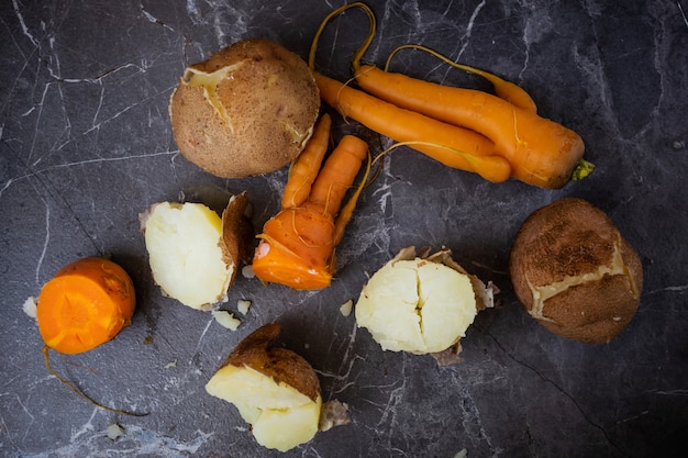 Boiled potatoes and carrots lie on a dark gray background. 