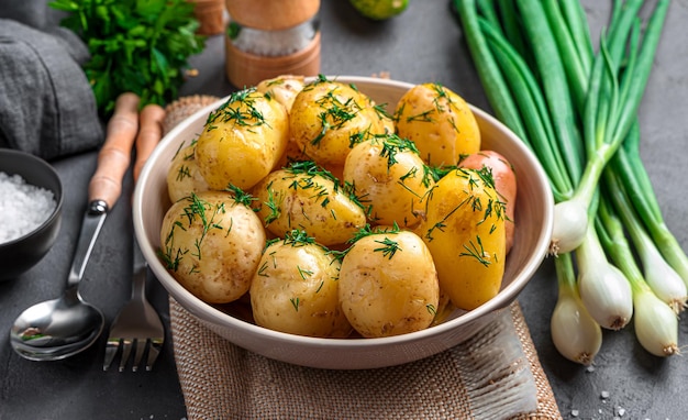 Boiled potatoes with dill and butter closeup on a dark background