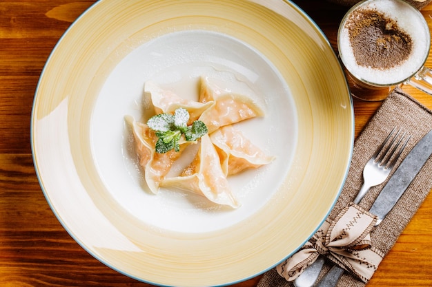 Boiled prepared homemade russian dumplings or pelmeni with pumpkin on the plate with fresh mintcooking culinary and food concept