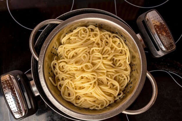 Boiled readymade spaghetti toss in a colander view from above