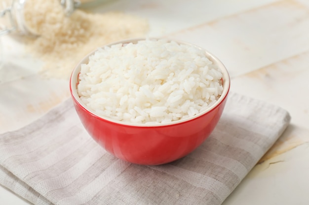 Boiled rice in bowl on white wooden table