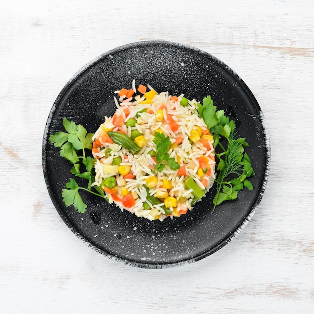 Boiled rice and vegetables Risotto In a black plate Top view Free copy space