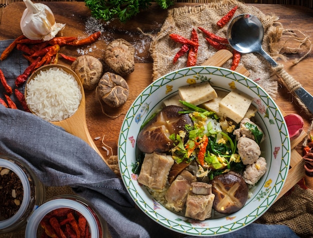 Boiled rice with pork, porn bone and thai pork sausage in bowl.