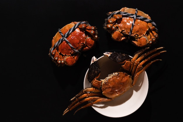 Boiled Shanghai hairy crab or Chinese mitten crab (Eriocheir sinensis) with Chili and herb on black background