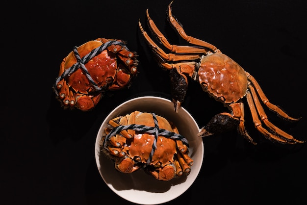 Boiled Shanghai hairy crab or Chinese mitten crab (Eriocheir sinensis) with Chili and herb on black background