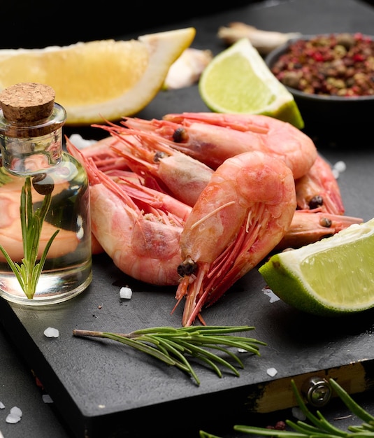 Boiled shrimp on a board lemon slices spices on a black background