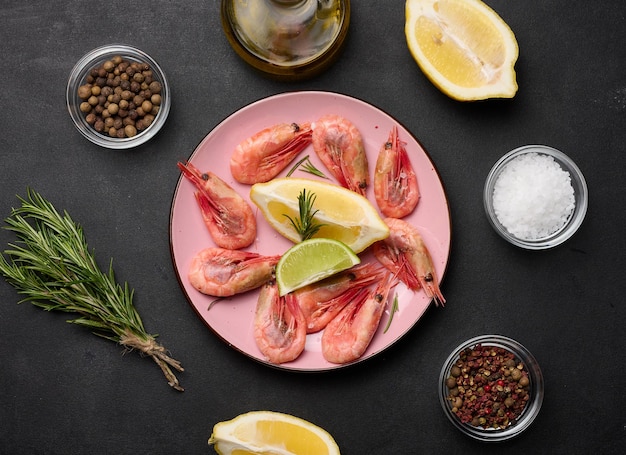 Boiled shrimp lemon and lime slices spices on a black table top view