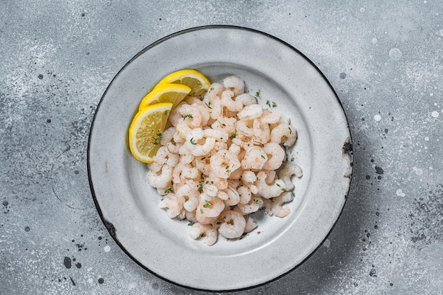 Boiled shrimps seafood with lemon herbs and spice prawns peeled Gray background top view