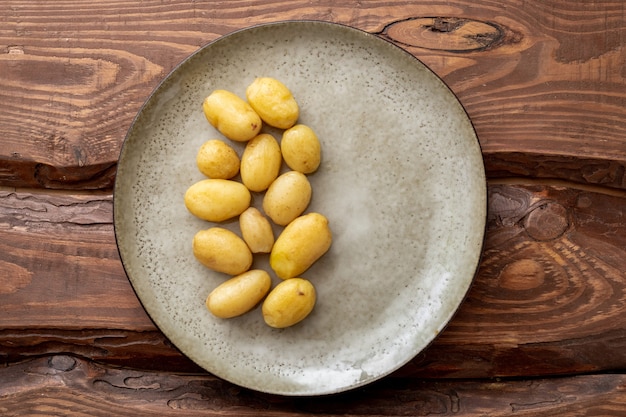 Boiled young small potatoes on a plate on a wooden background.