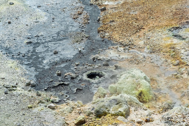 Boiling fumaroles and sulfur deposits at the hydrothermal outlet on the shore of the hot lake in the caldera of the Golovnin volcano on the island of Kunashir