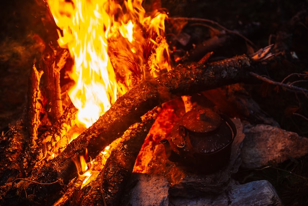 Boiling of tea in kettle on bonfire with large firewood