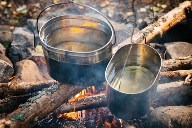 Boiling water in hiking bowlers over a fire in the forest travel and tourism