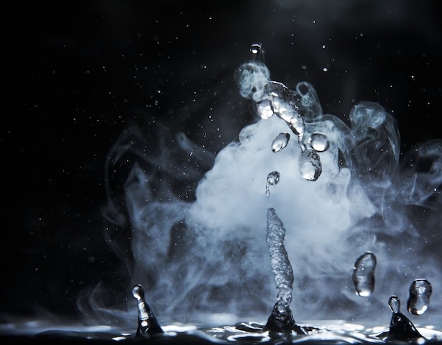 Boiling water splash with steam on black background closeup