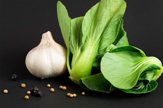 bok choy or chinese cabbage and garlic on black background