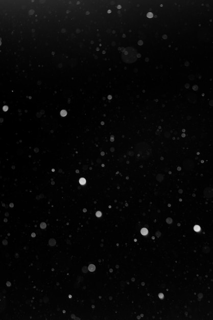 A bokeh of white snow on a black background