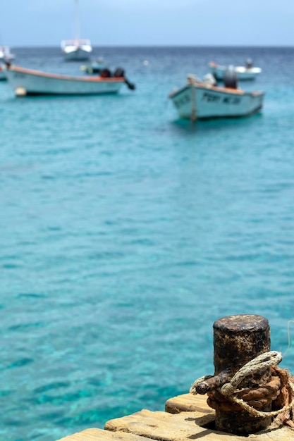 Bollard for mooring boats in the foreground with boats on the Caribbean Sea in Curazao