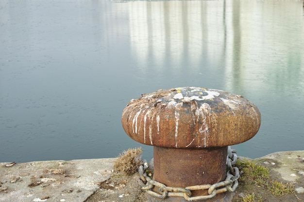 A bollard port by a harbour Rusty mooring bollard cast iron at pier shore Sky and water background copyspace Securing anchor point to prevent vessels from drifting away due tide current and wind