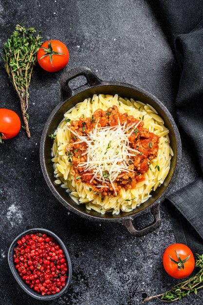 Bolognese pasta, risone with ground beef in a plate on Black table. 