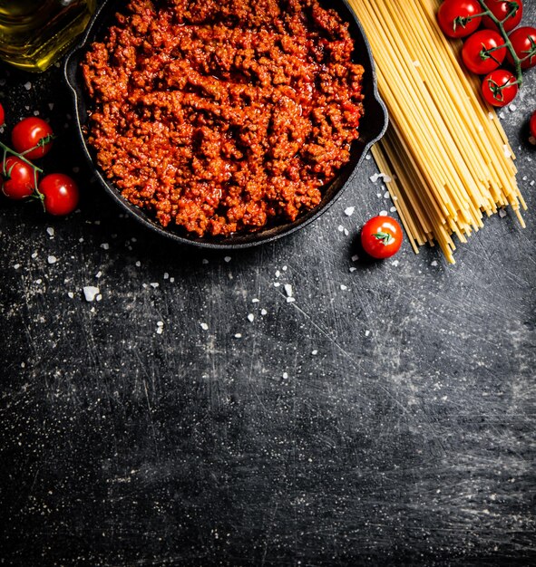 Bolognese sauce in a pan with tomatoes and pasta dry