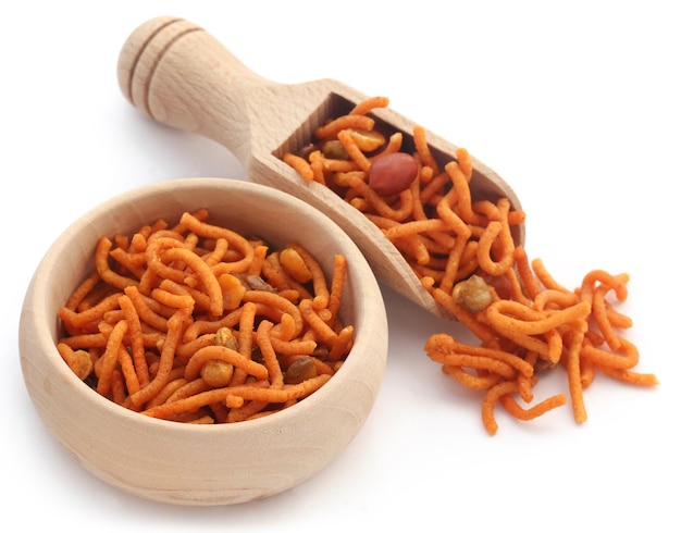 Bombay mix in wooden bowl and scoop over white background