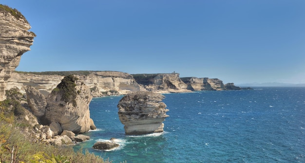 Bonifacio coastline with limestone cliff in the sea under clear blue sky in Corsica