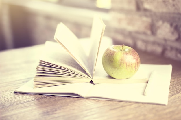 Book apple and blank diary on a wooden table