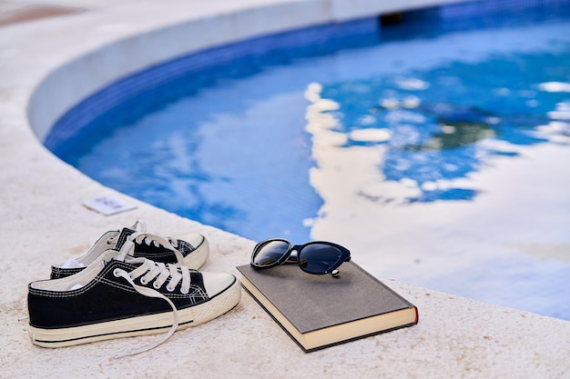 Book goggles and slippers on the edge of the swimming pool