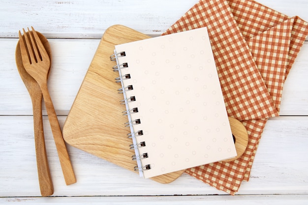 Book notepad paper on chopping cutting board and tablecloth on white table , a recipes food  for healthy habits shot note  