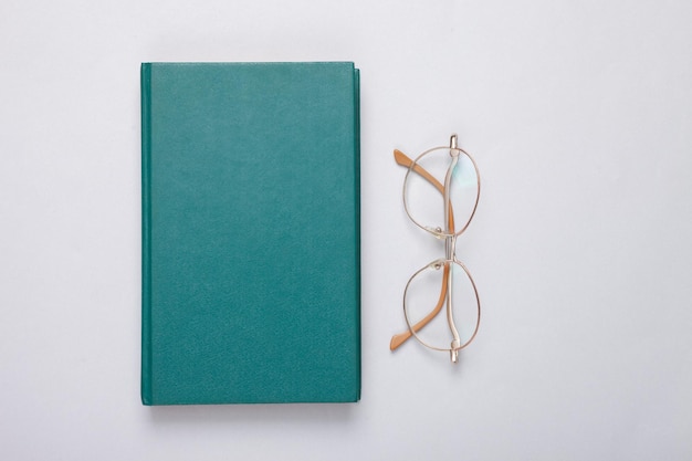 Book and optical eye glasses on gray background